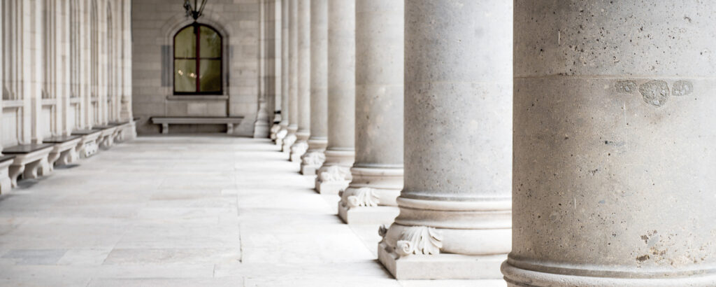 A view of architectural columns in a building, featuring a bench positioned centrally between them.